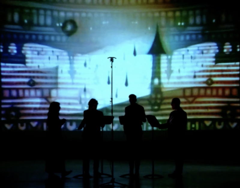 Silhouetted musicians perform in front of a light blue and white animated projection of a fantastical building and falling te
