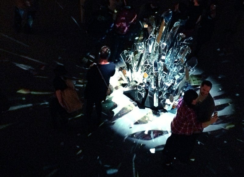 Scott N Andrew's "Glimmer" features a large, jagged crystal sculpture reflecting light in a dark room with blurred figures.